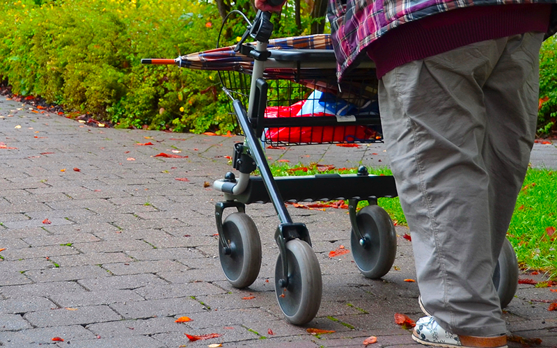 Lady walking using a rollator with basket